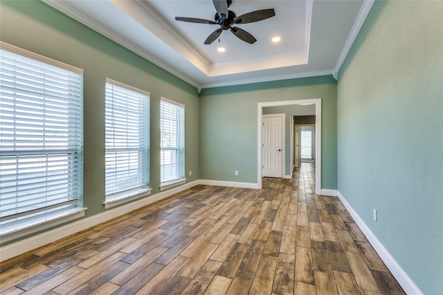 spare room featuring a tray ceiling, crown molding, hardwood / wood-style floors, and ceiling fan