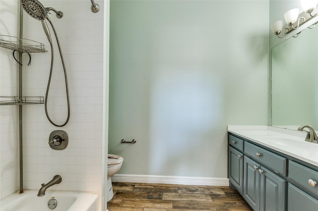 full bathroom featuring tiled shower / bath combo, toilet, wood-type flooring, and vanity