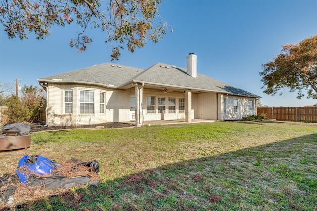 rear view of house with ceiling fan, a patio area, and a lawn