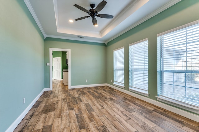 spare room with ceiling fan, a healthy amount of sunlight, wood-type flooring, and crown molding