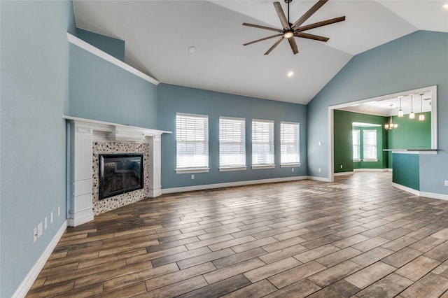 unfurnished living room featuring wood-type flooring, ceiling fan with notable chandelier, lofted ceiling, and a tiled fireplace