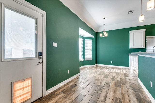 unfurnished dining area with hardwood / wood-style floors, an inviting chandelier, lofted ceiling, and sink