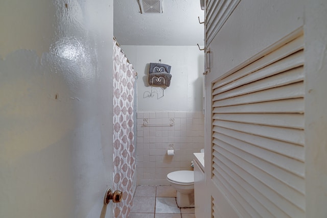 bathroom featuring a shower with curtain, tile patterned floors, toilet, and tile walls