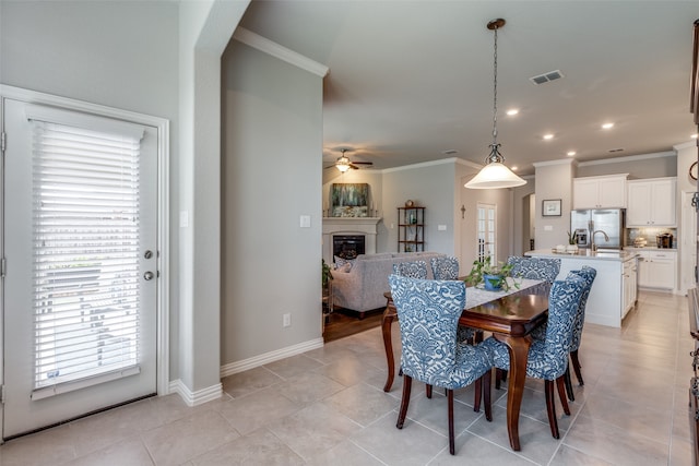 dining area featuring ceiling fan, sink, ornamental molding, and light tile patterned flooring