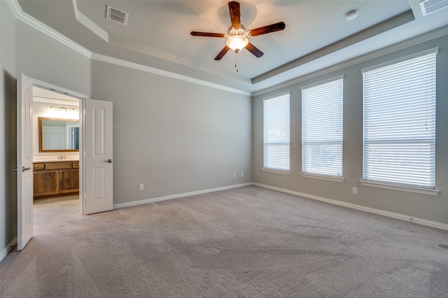 carpeted spare room with a raised ceiling, ceiling fan, and ornamental molding