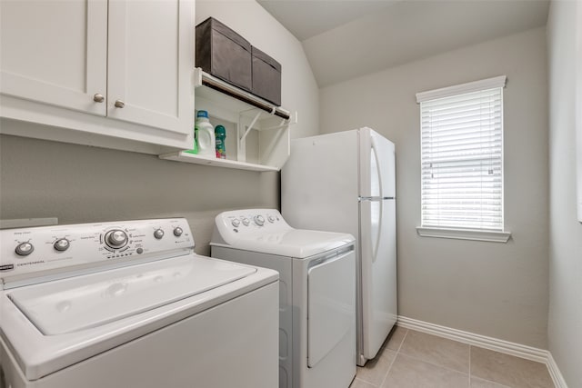 laundry room with light tile patterned flooring, washing machine and clothes dryer, and cabinets