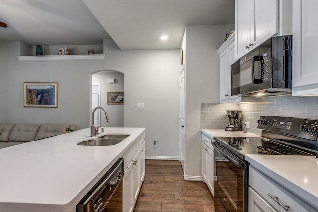 kitchen with white cabinetry, a center island with sink, dark wood-type flooring, black appliances, and sink