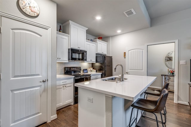 kitchen with a kitchen bar, white cabinets, black appliances, and a kitchen island with sink