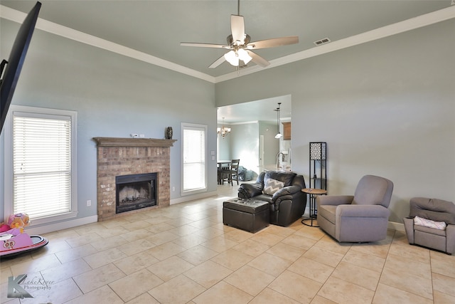 tiled living room with a brick fireplace, ceiling fan with notable chandelier, ornamental molding, and a healthy amount of sunlight