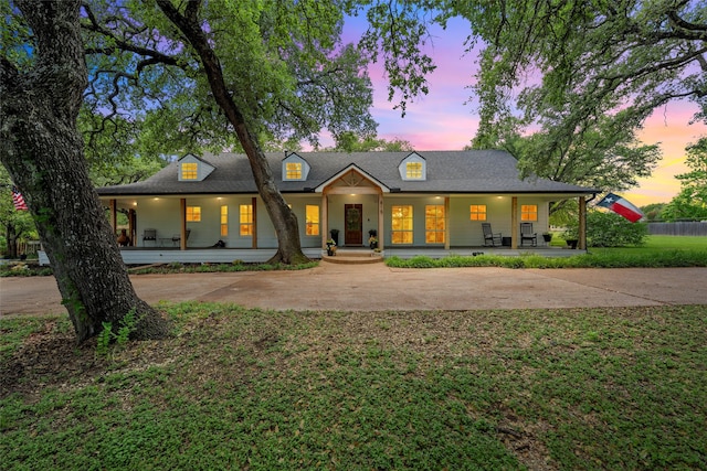 view of front of property with covered porch and a lawn