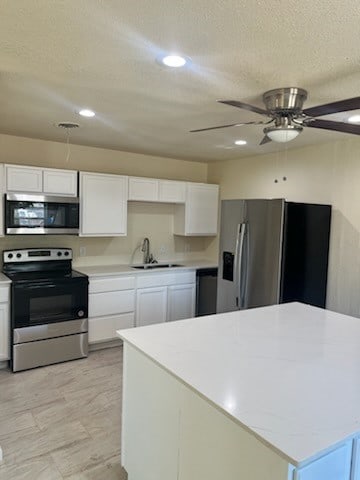 kitchen featuring ceiling fan, a textured ceiling, white cabinetry, sink, and stainless steel appliances