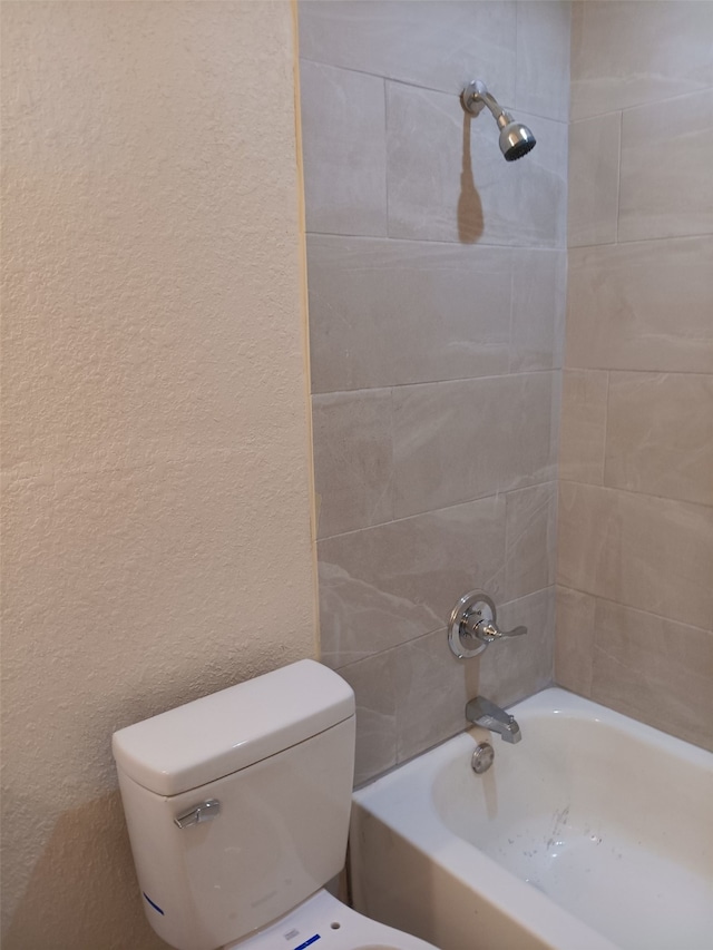 bathroom featuring toilet and tiled shower / bath combo