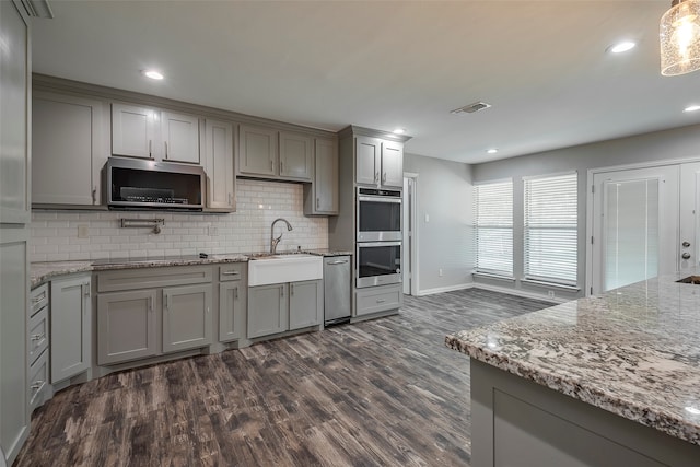 kitchen featuring dark wood-type flooring, decorative backsplash, light stone counters, and stainless steel appliances