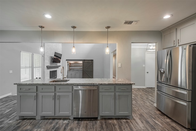 kitchen with gray cabinetry, stainless steel appliances, sink, decorative light fixtures, and dark hardwood / wood-style flooring