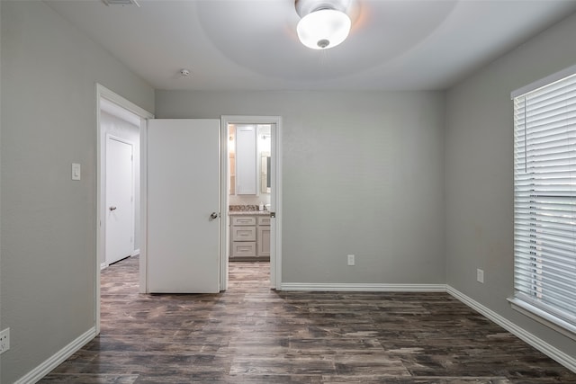 unfurnished bedroom with dark hardwood / wood-style flooring, ensuite bathroom, and ceiling fan