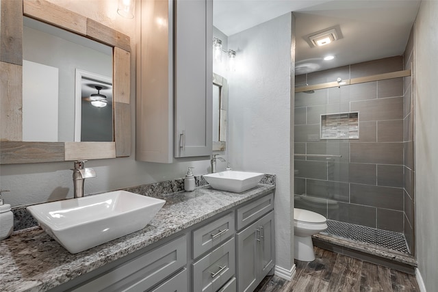 bathroom featuring toilet, hardwood / wood-style floors, vanity, and a tile shower