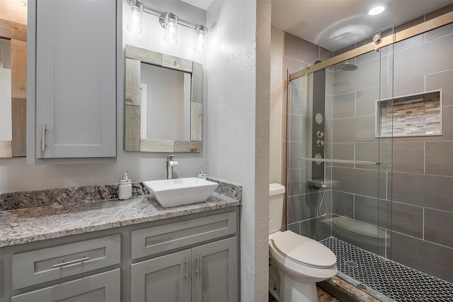 bathroom with a shower with door, vanity, and toilet