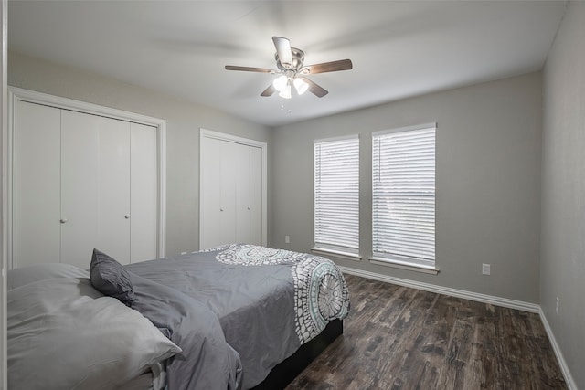 bedroom featuring ceiling fan, multiple closets, and dark hardwood / wood-style floors