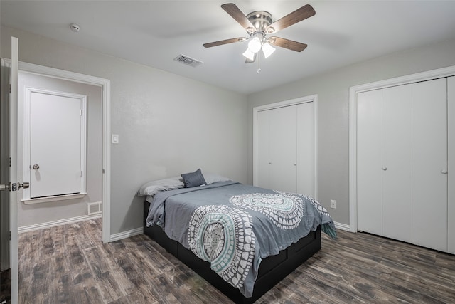 bedroom featuring multiple closets, dark hardwood / wood-style floors, and ceiling fan