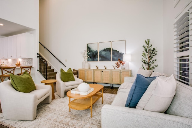 living area with stairs, a high ceiling, and wood finished floors