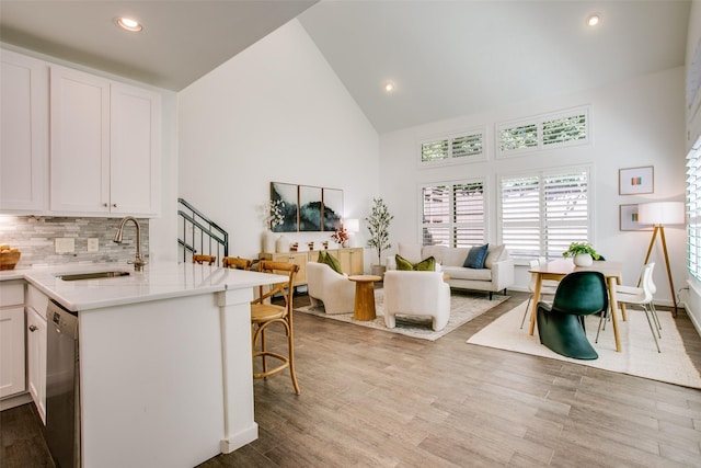 kitchen featuring white cabinets, a breakfast bar, open floor plan, a sink, and stainless steel dishwasher