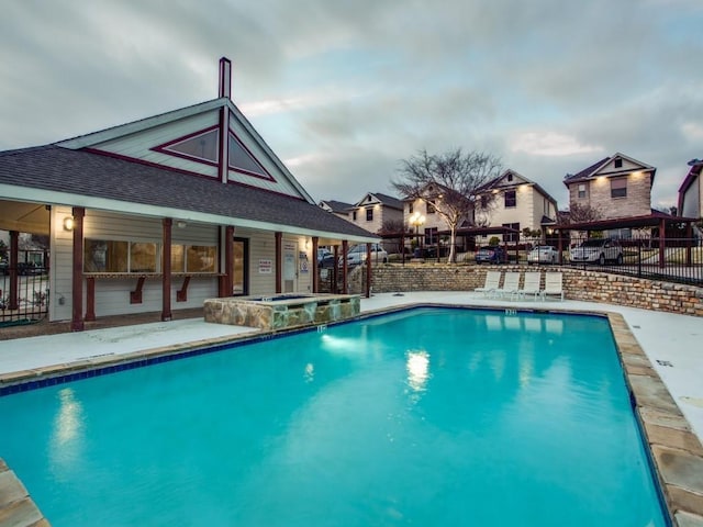 pool featuring a community hot tub, a patio, and fence