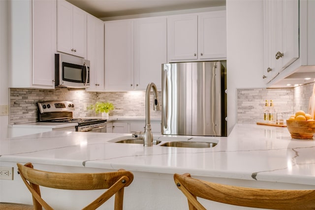 kitchen with stainless steel appliances, white cabinetry, and a kitchen breakfast bar