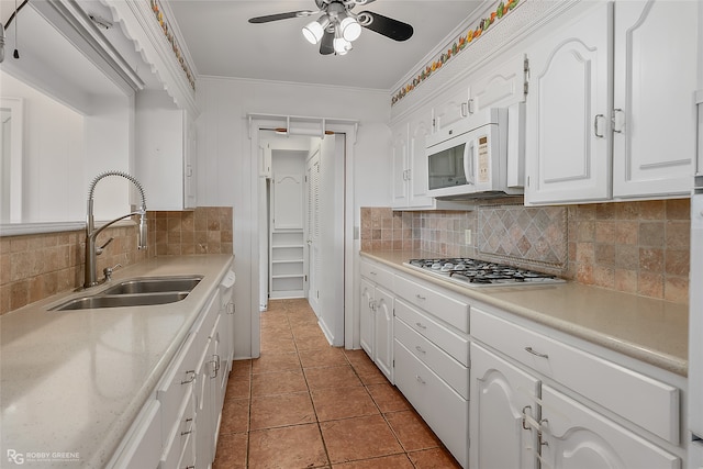 kitchen featuring light tile patterned flooring, sink, backsplash, white cabinetry, and crown molding