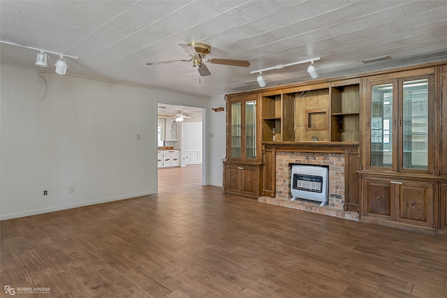 unfurnished living room featuring dark wood-type flooring, a fireplace, rail lighting, and ceiling fan