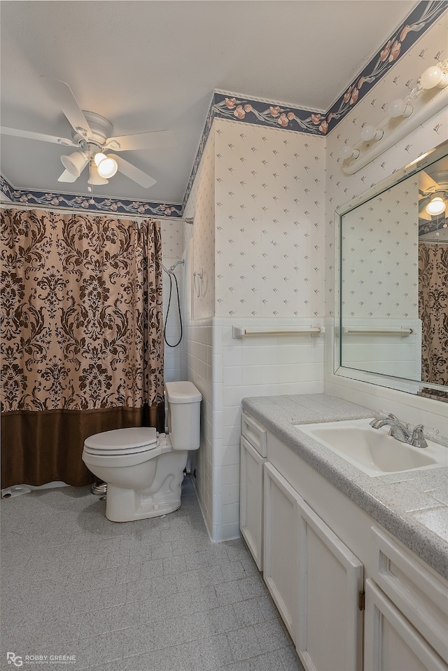 bathroom featuring toilet, ceiling fan, tile walls, walk in shower, and vanity