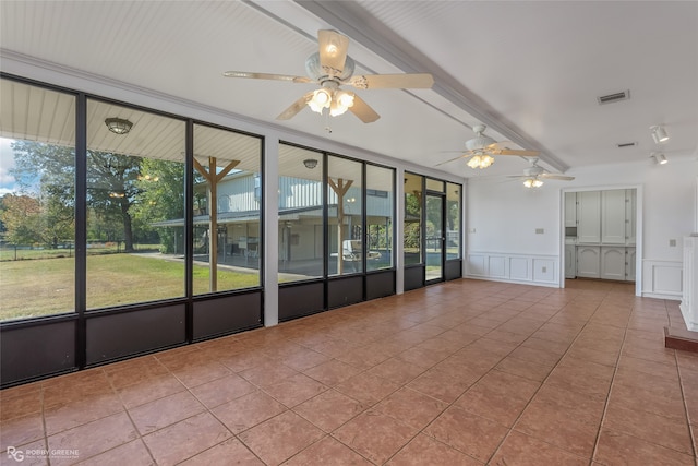 empty room with beamed ceiling, light tile patterned floors, and plenty of natural light