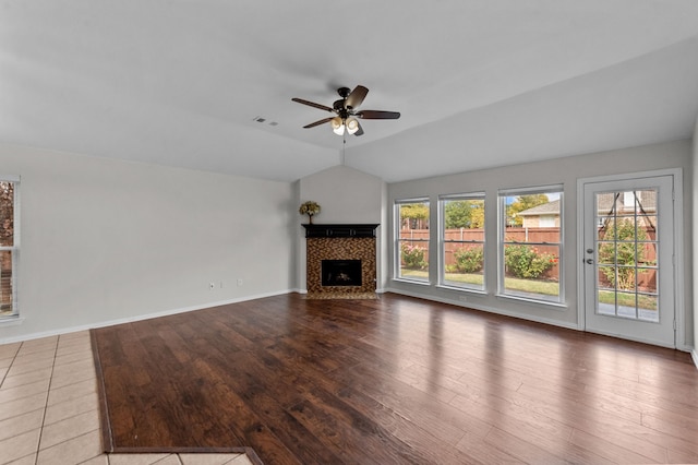 unfurnished living room featuring lofted ceiling, a tiled fireplace, light wood-type flooring, and ceiling fan