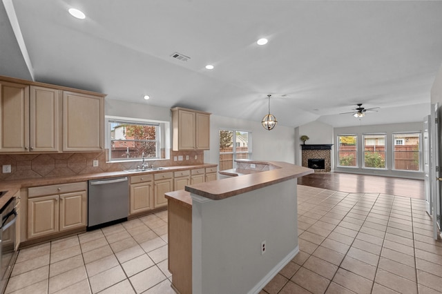 kitchen with lofted ceiling, backsplash, stainless steel dishwasher, a brick fireplace, and ceiling fan with notable chandelier