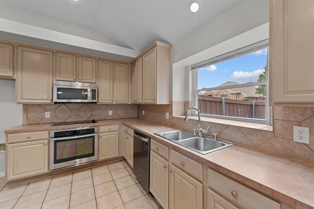 kitchen featuring sink, light tile patterned flooring, vaulted ceiling, appliances with stainless steel finishes, and tasteful backsplash