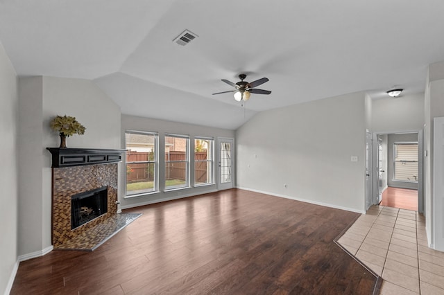 living room featuring ceiling fan, hardwood / wood-style flooring, lofted ceiling, and a tile fireplace