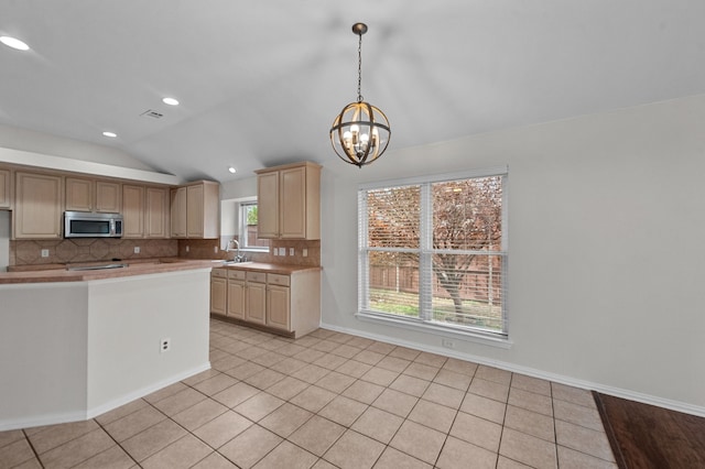 kitchen featuring a notable chandelier, decorative backsplash, sink, and vaulted ceiling