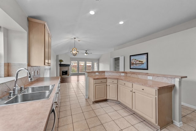 kitchen featuring light brown cabinets, sink, a brick fireplace, pendant lighting, and tasteful backsplash