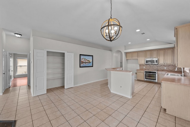 kitchen featuring lofted ceiling, light brown cabinets, sink, pendant lighting, and appliances with stainless steel finishes