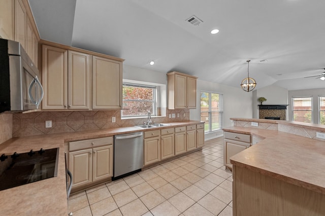 kitchen featuring appliances with stainless steel finishes, sink, backsplash, vaulted ceiling, and decorative light fixtures