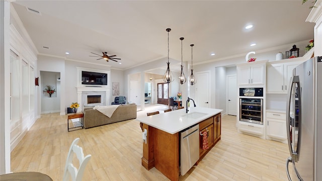 kitchen with stainless steel appliances, a kitchen island with sink, sink, and white cabinets