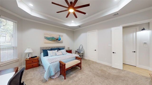 carpeted bedroom featuring ceiling fan, ornamental molding, and a tray ceiling