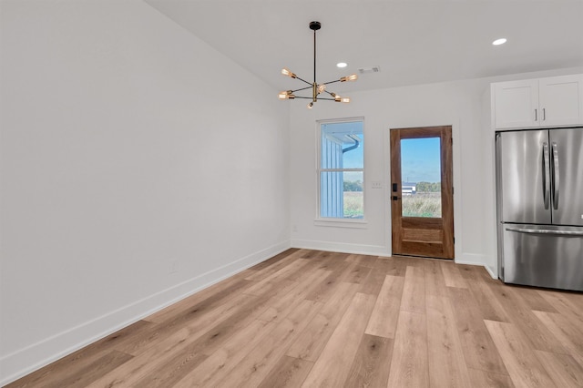 unfurnished dining area with light wood-type flooring and a chandelier