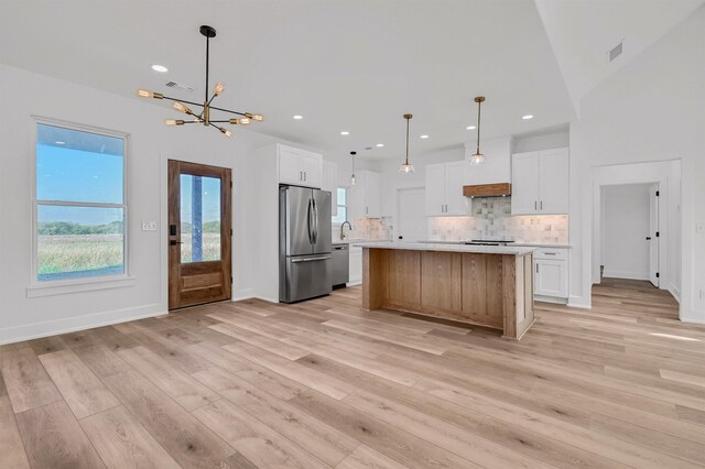 kitchen featuring white cabinetry, stainless steel appliances, a center island, decorative backsplash, and pendant lighting