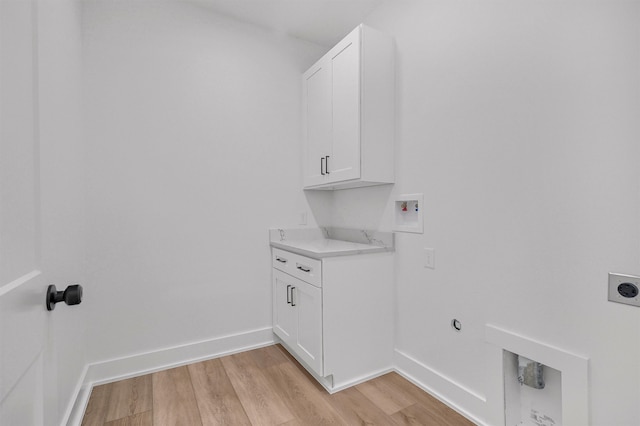 clothes washing area featuring cabinets, light hardwood / wood-style floors, hookup for a washing machine, and electric dryer hookup