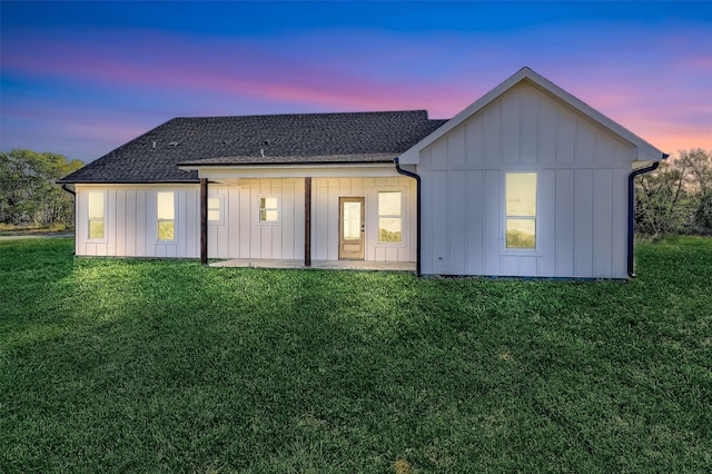 back house at dusk featuring a yard