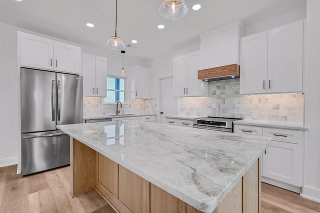 kitchen featuring white cabinetry, a center island, decorative light fixtures, sink, and appliances with stainless steel finishes