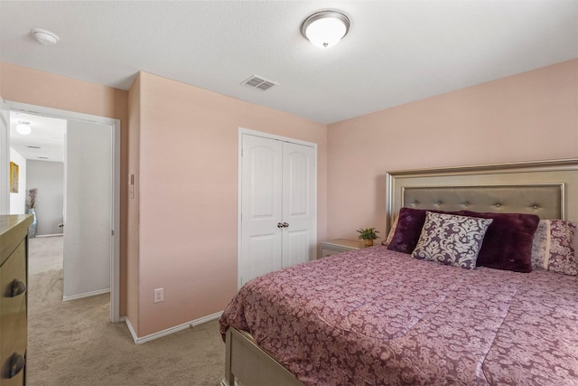 bedroom with baseboards, light colored carpet, visible vents, and a closet