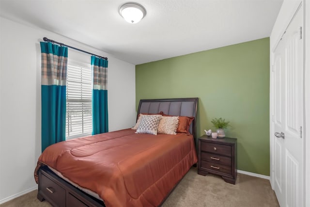 bedroom featuring light colored carpet, baseboards, and a closet