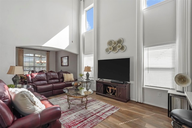 living area with a wealth of natural light, wood finished floors, and a chandelier
