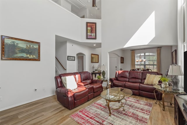 living room with a towering ceiling, light hardwood / wood-style flooring, and a chandelier